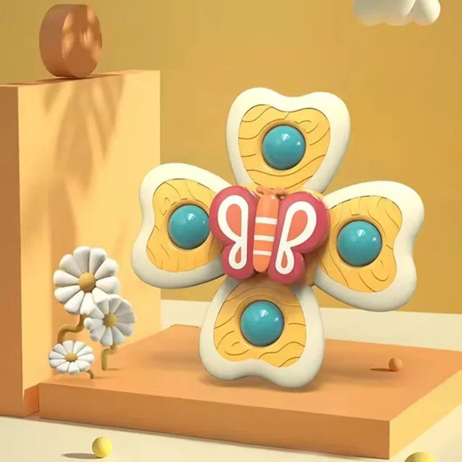 A colorful, bee-shaped suction cup bath toy with orange and white patterns sits on a wooden surface.