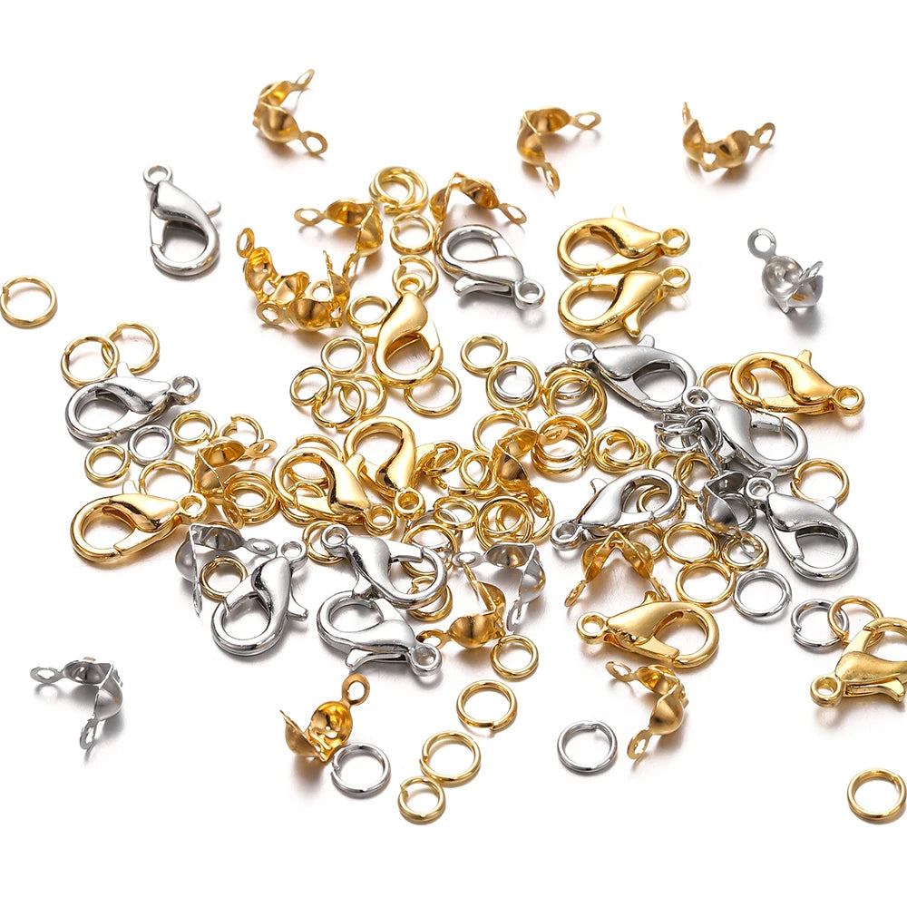A collection of gold and silver jewelry making components including lobster clasps, jump rings, and crimps.