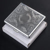 Classic stainless steel cigarette case with an embossed swirling pattern resting in its white presentation box.