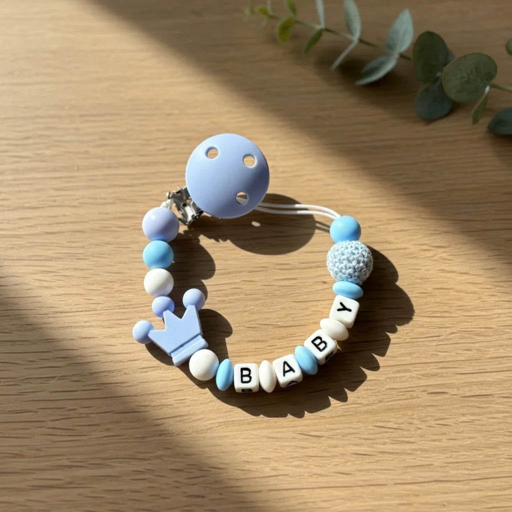 A personalized baby pacifier clip featuring various pastel colored silicone beads and the name BABY.
