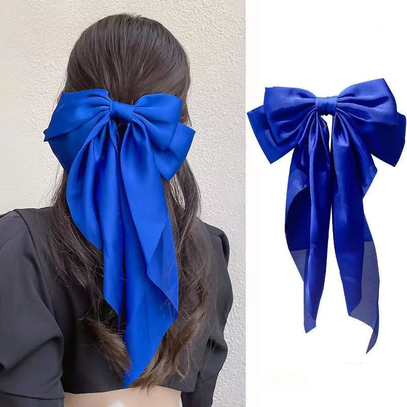 A royal blue silk bow hair clip tied in a large bow shape