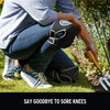 A person wearing dark jeans is shown using a black soft foam kneepad on their knee while gardening.