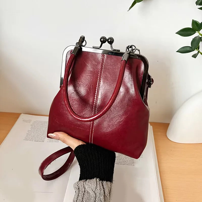 A deep burgundy vintage brown PU leather crossbody handbag is shown resting on a white surface.