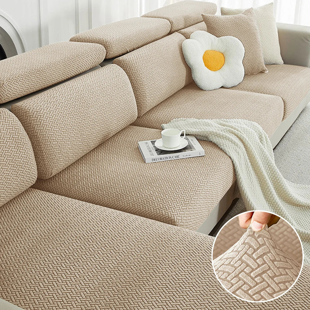 A beige jacquard elastic sofa slipcover featuring a woven texture and decorative pillows.