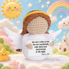 A handmade crochet pocket hug doll with wings and a smiling face is shown against a soft, cloudy background.
