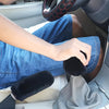 A hand is adjusting a plush black car gear shift and handbrake cover set inside a vehicle.