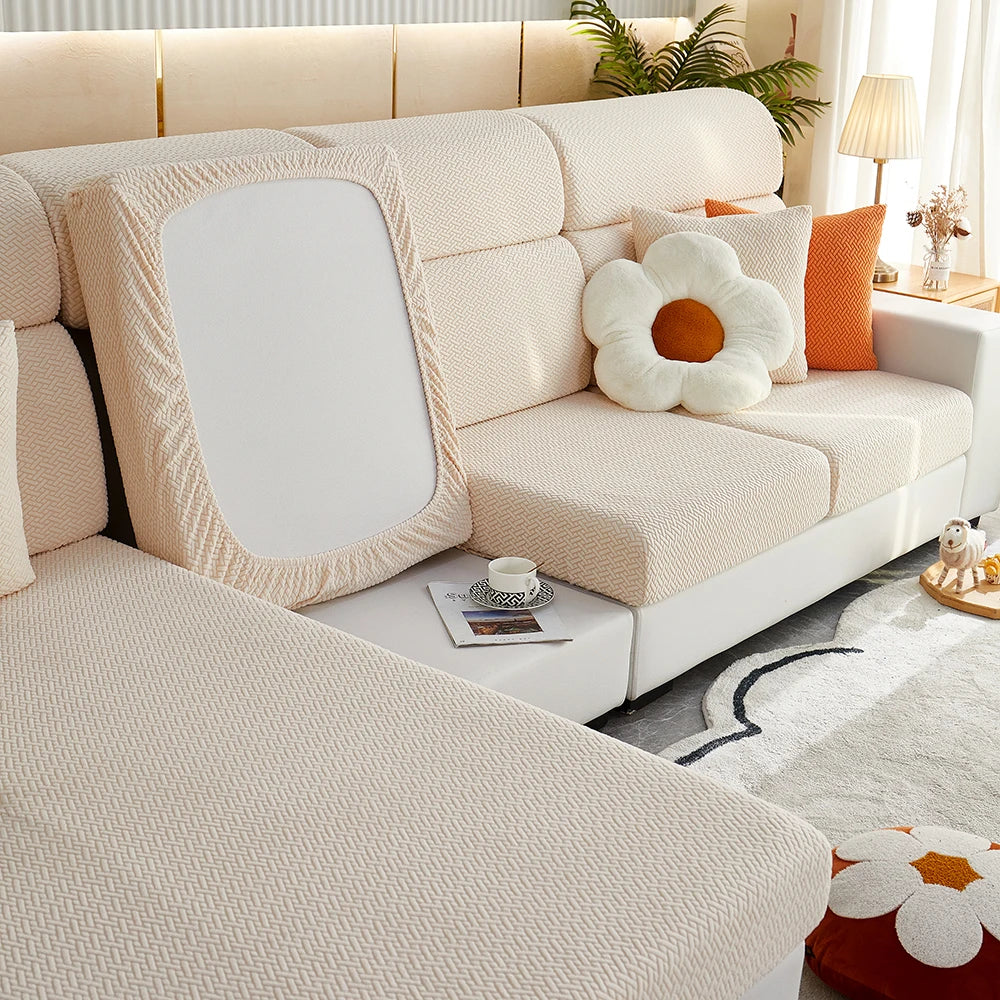 A light beige elegant sofa slipcover featuring tufted upholstery and decorative pillows.