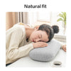 A woman rests her head on a gray memory foam travel neck pillow with a beige cover.