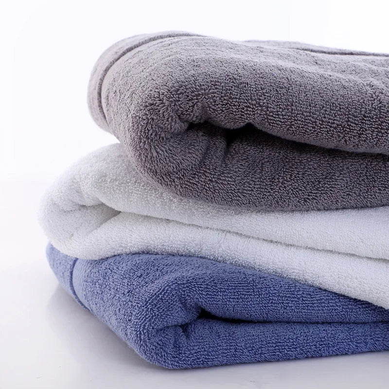 A stack of soft gray and white bath towels folded on a white surface.