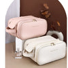 A light pink cosmetic bag and a white cosmetic bag are displayed against a brown background with some dried leaves.