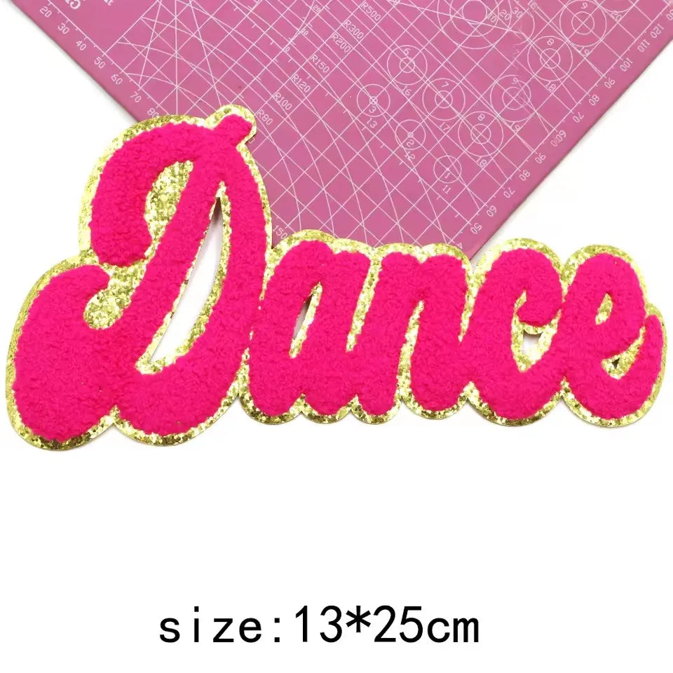 Pink glitter felt letter patch spelling the word Dance with a pink grid background