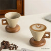 A ceramic coffee mug with a wood base and spoon is displayed on a white surface.