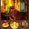 A DIY book nook kit featuring a miniature bookshelf room scene with potted plants and warm lighting.