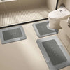 Three rectangular floor mats with the word HOME printed on them placed in front of a white toilet.