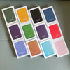 A collection of sixteen leather wallet cases in various colors arranged in a grid.