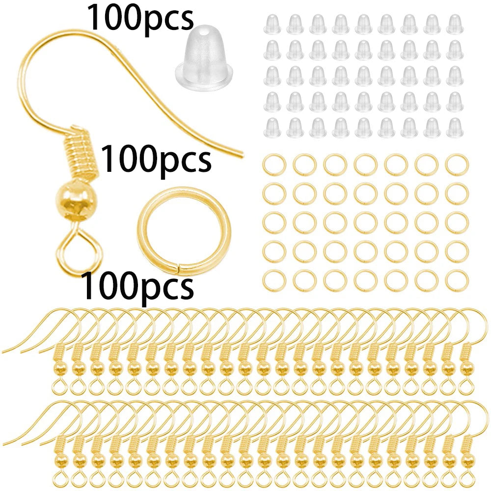 A collection of gold-colored jewelry making components including lobster clasps, jump rings, and crimps.