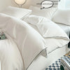 A close-up of a white duvet cover set with pillows and a decorative throw, showing the fabric texture.