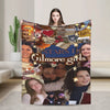A colorful throw blanket featuring portraits of Gilmore Girls characters and text.