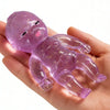 A hand holds a translucent purple glitter squishy stress relief toy with a baby-like face.