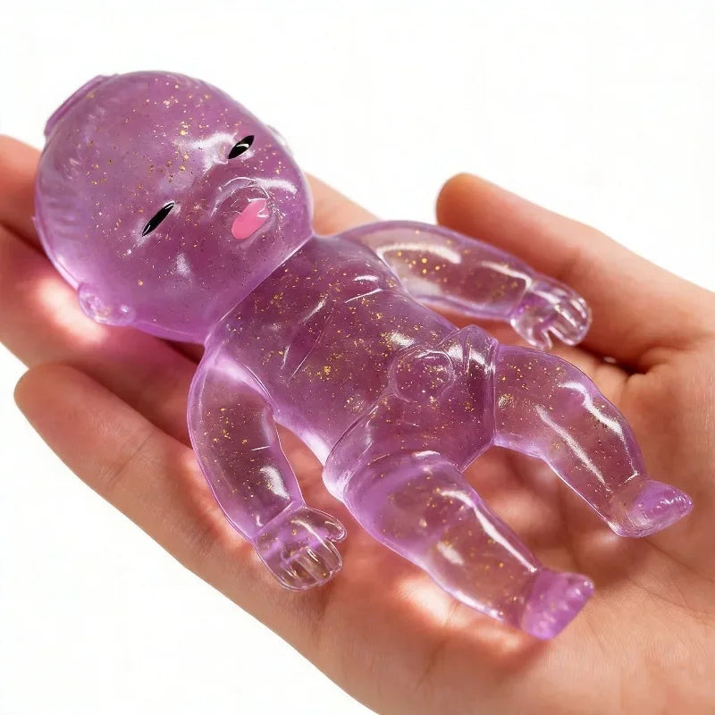 A hand holds a translucent purple glitter squishy stress relief toy with a baby-like face.