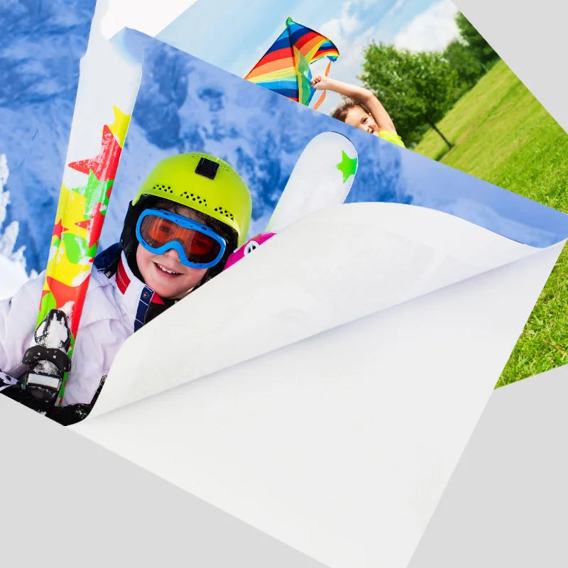 A child wearing a yellow helmet and goggles is smiling while holding a colorful kite against a blue sky.
