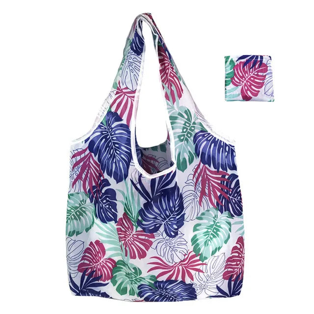 A white and purple tropical leaf patterned reusable nylon shopping tote bag.