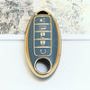 A close-up of a gold-colored soft TPU car key fob cover with five buttons mounted on a light blue background.