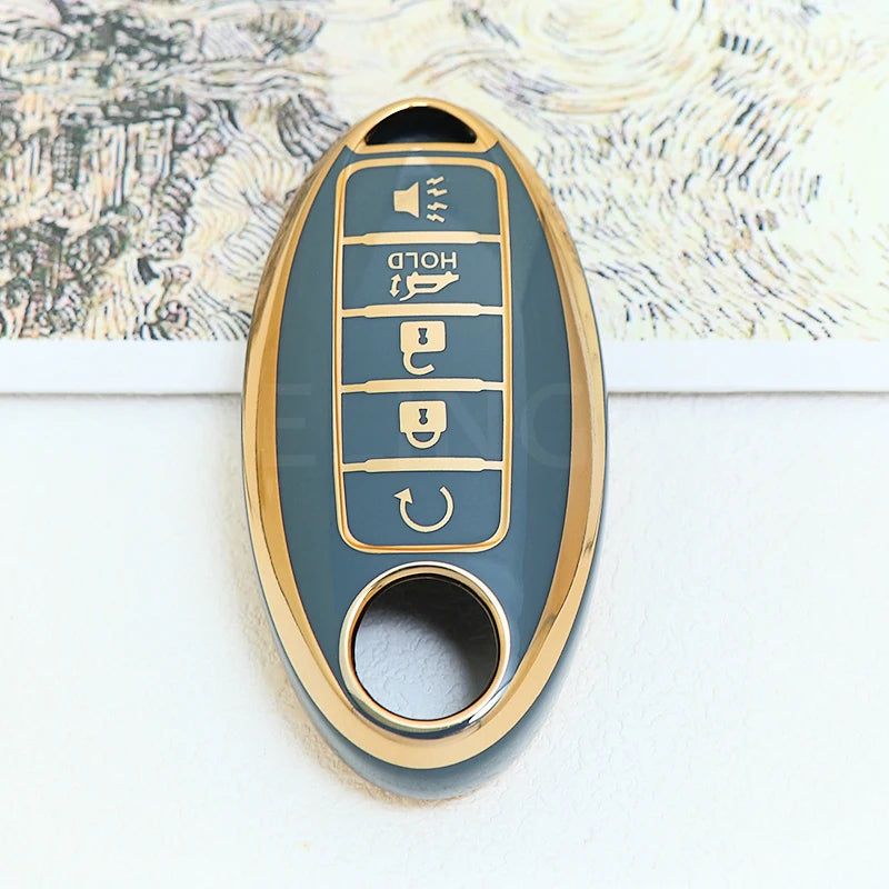 A close-up of a gold-colored soft TPU car key fob cover with five buttons mounted on a light blue background.