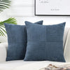 A set of two navy blue corduroy patchwork throw pillow covers displayed on a white sofa.