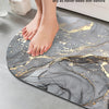 A person's feet are stepping onto a gray and gold non-slip bathroom mat, demonstrating the quick-dry feature.