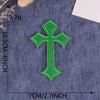 A single vibrant green embroidered cross patch on a dark blue fabric background.