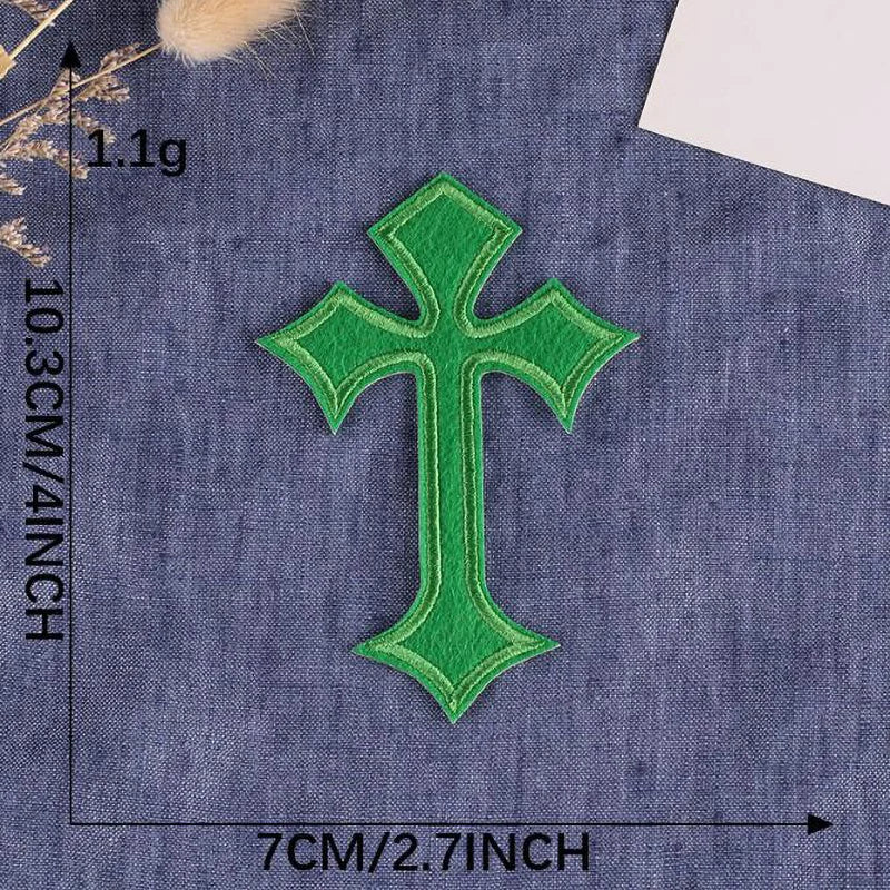 A single vibrant green embroidered cross patch on a dark blue fabric background.