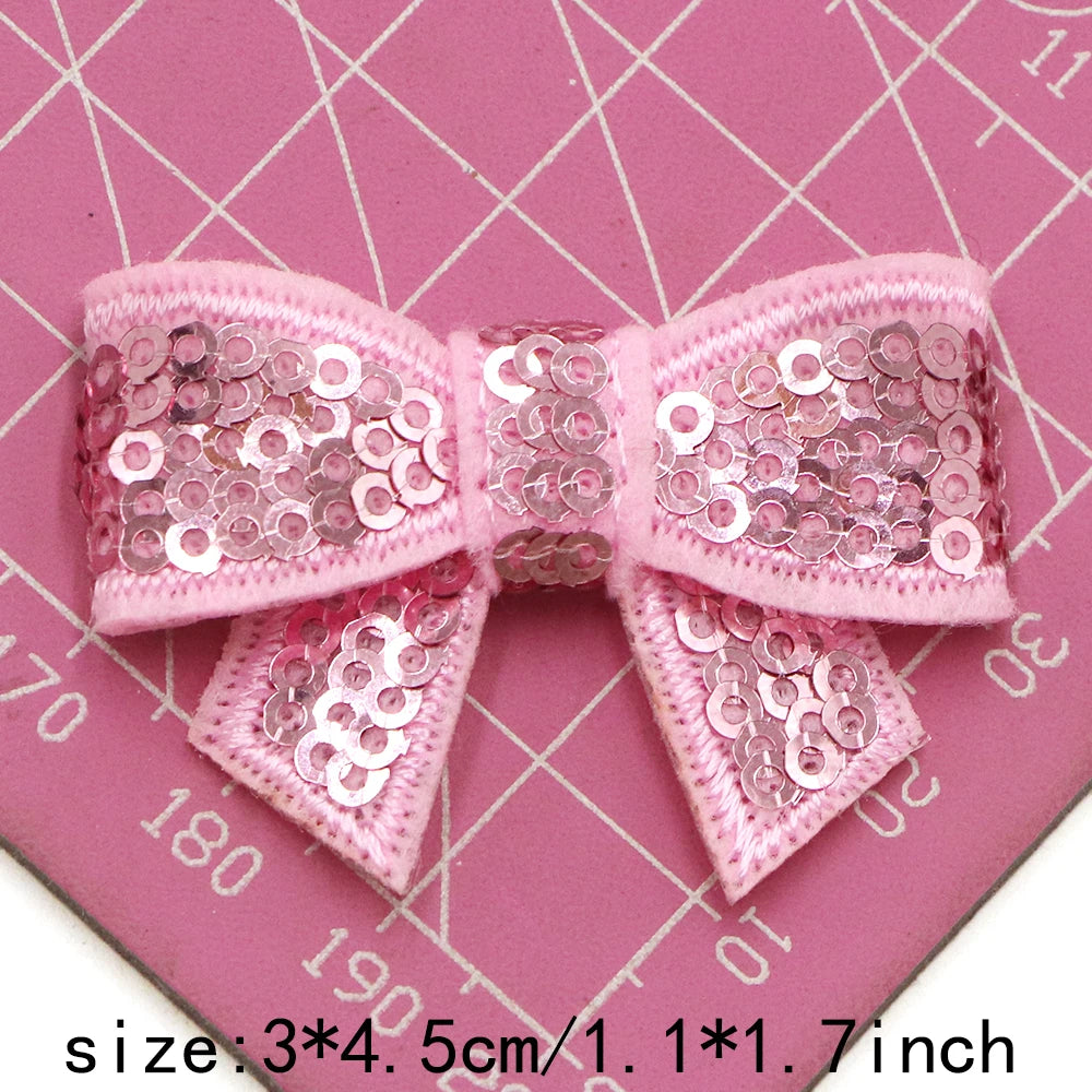 Pink sequin bow patches for DIY crafts shown on a pink cutting mat