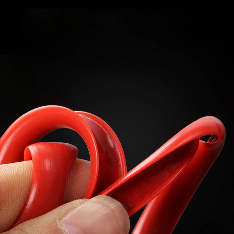 A hand is holding a red car wheel rim protector trim, showing its curved shape and texture against a dark background.