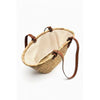 A handwoven straw tote bag with a light beige lining and brown leather straps.