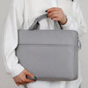 A person holds a gray waterproof nylon laptop sleeve for notebooks against a white sweater.