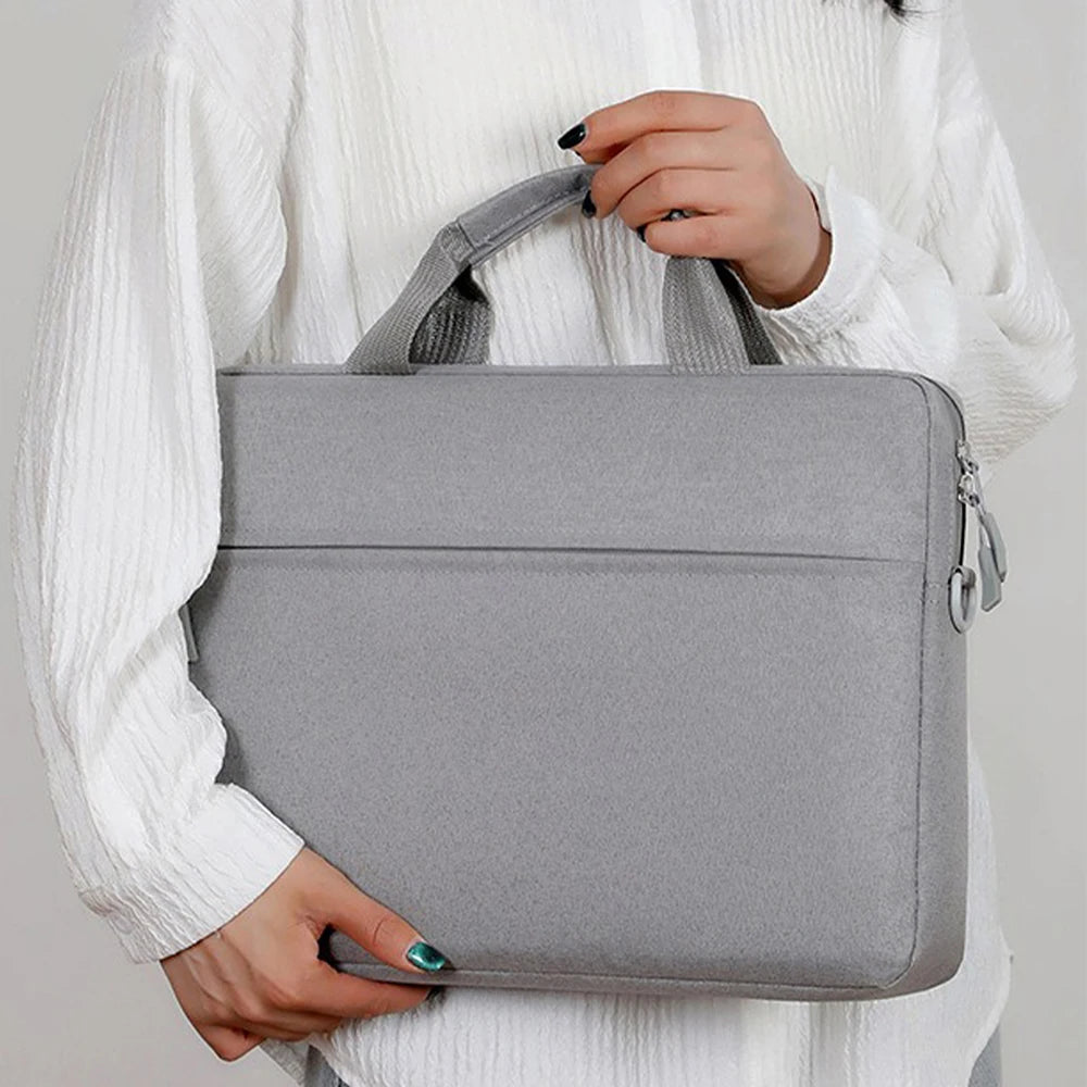 A person holds a gray waterproof nylon laptop sleeve for notebooks against a white sweater.