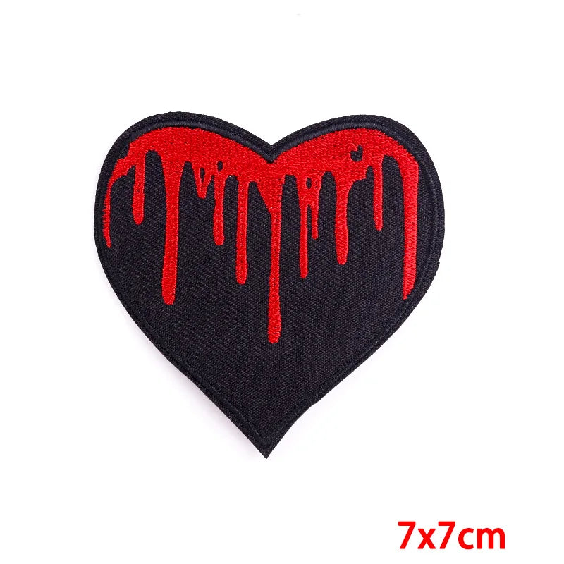 A black heart shaped patch with a dripping red paint effect on the surface.