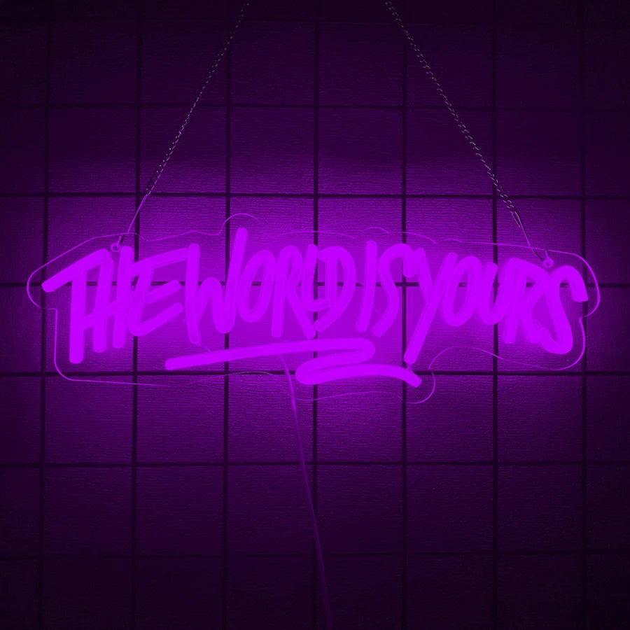 A neon sign spelling out THE WORLD IS YOURS in bright purple light against a dark grid background.
