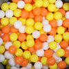 A large pile of colorful plastic ball pit balls in shades of orange, yellow, and white.