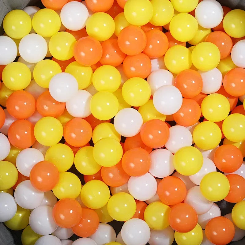 A large pile of colorful plastic ball pit balls in shades of orange, yellow, and white.