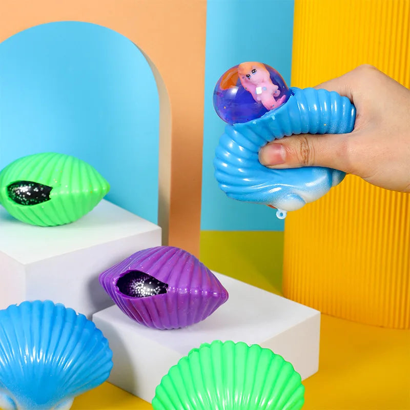 A hand squeezes a blue mermaid shell fidget toy against a light blue background.