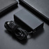 Schwarzer 100W USB-C PD Laptop-Ladegerät und Kabel auf dunkler Oberfläche.