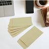 A stack of light tan kraft paper cash envelopes is displayed on a white surface next to a laptop and a smartphone.