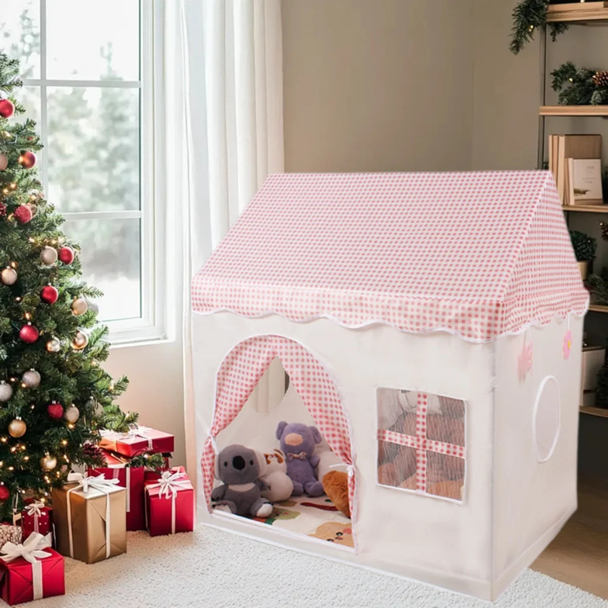 A white playhouse tent with a pink gingham roof and arched entrance, decorated with greenery and gifts.