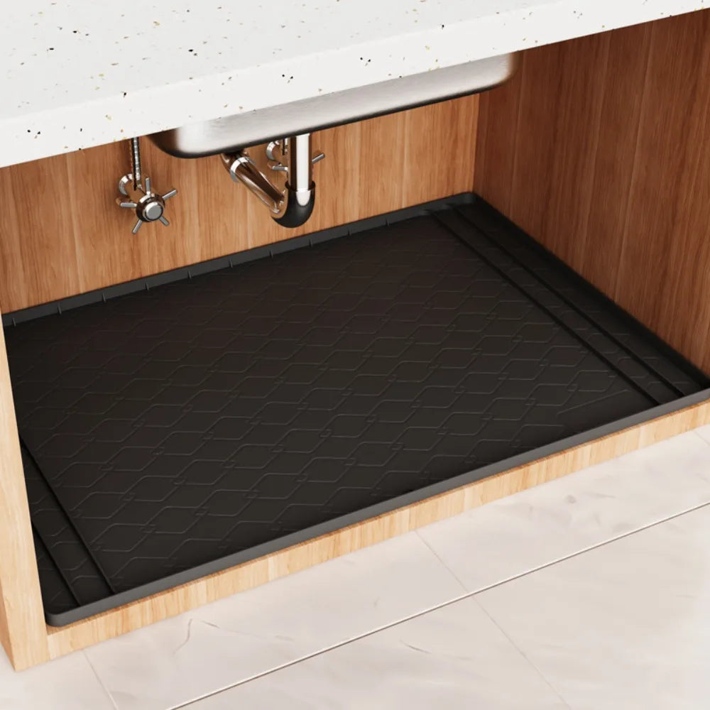 A black silicone mat is placed inside an under sink cabinet to protect the surface.