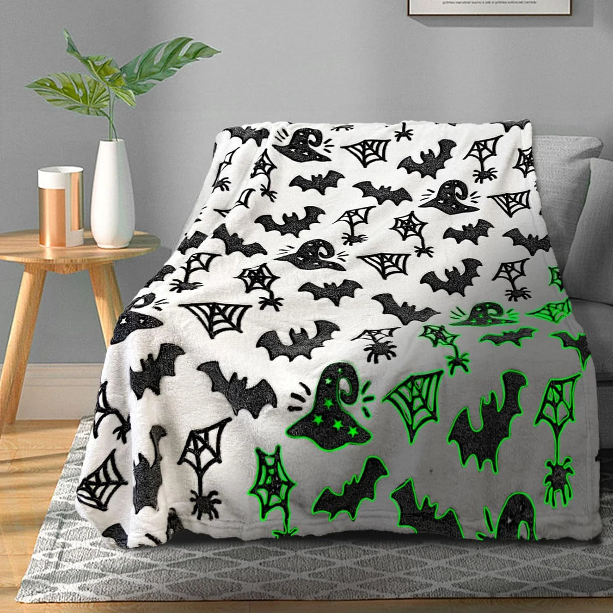 Schwarz-weißes Leuchtkraft-Fledermaus- und Spinnenmuster-Halloween-Decke auf grauem Teppich.