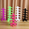 A set of colorful, stackable display stands for eyeglasses and sunglasses in pink, green, white, and black.