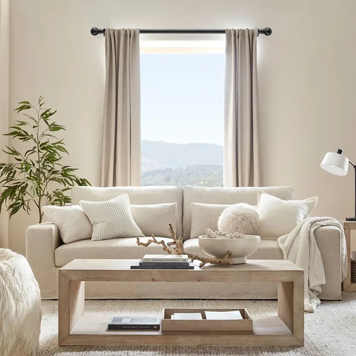 A living room scene featuring a light beige sofa, sheer curtains, and a wooden coffee table.