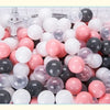 A large assortment of colorful plastic balls in various shades of pink, white, and gray are displayed in a white basket.
